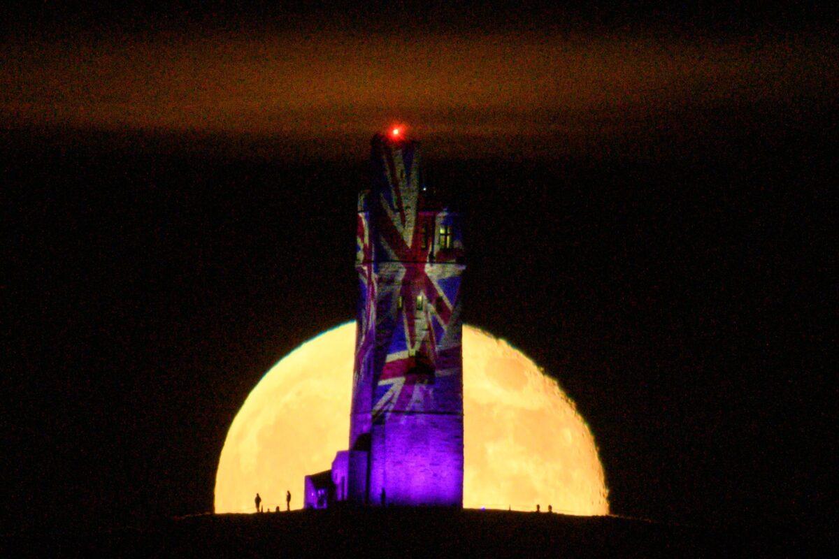 The moon rises behind Victoria Tower, which had been illuminated with Union Flags to mark the 75th anniversary of VE Day, on Castle Hill overlooking Huddersfield, northern England on May 8, 2020. (Oli Scarff/AFP via Getty Images)