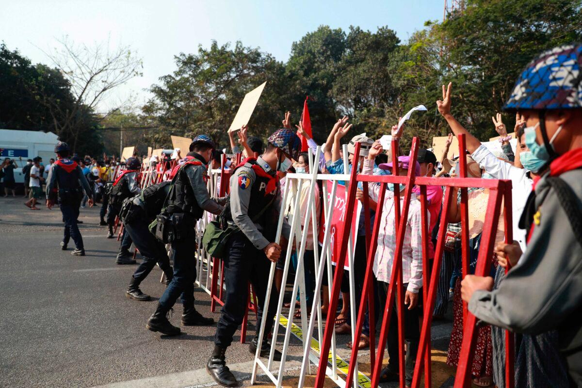 Police security fix road barricades blocking protesters in Yangon, Burma, on Feb. 7, 2021. (AP Photo)