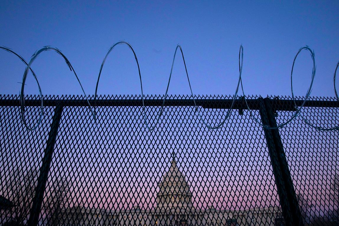 The U.S. Capitol, seen through barbed wire fencing at sunrise, in Washington on Feb. 8, 2021. (Sarah Silbiger/Getty Images)