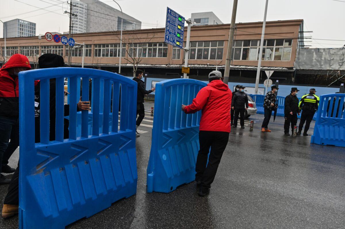 Workers place barriers outside the closed Huanan Seafood wholesale market during a visit by members of the World Health Organization (WHO) team, investigating the origins of the COVID-19 disease, in Wuhan, China's central Hubei province on Jan. 31, 2021. (Hector Retamal/AFP via Getty Images)