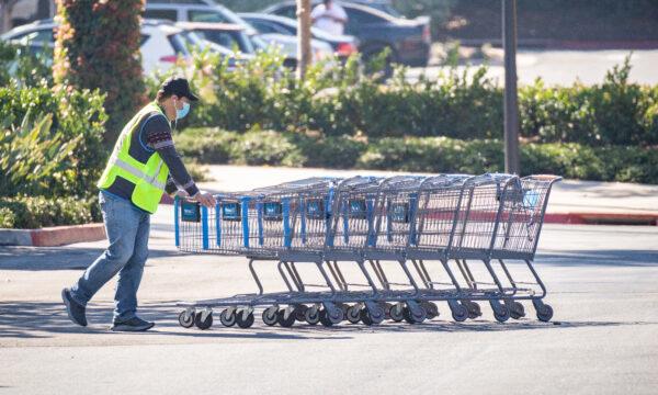 A worker pushes shopping carts in a Walmart parking lot in Irvine, Calif., on Feb. 5, 2021. (John Fredricks/The Epoch Times)