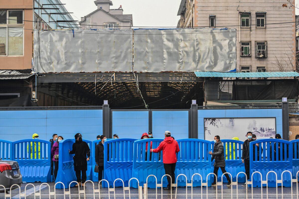 Workers place barriers outside the closed Huanan Seafood wholesale market during a visit by members of the World Health Organization (WHO) team, investigating the origins of the Covid-19 coronavirus, in Wuhan, China's central Hubei province on Jan. 31, 2021. (Hector Retamal/AFP via Getty Images)