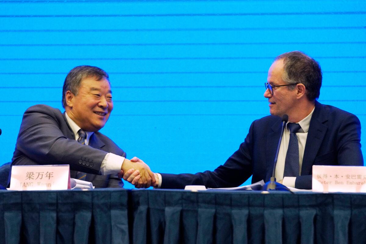 Peter Ben Embarek (right), one of the World Health Organization team members, shakes hands with his Chinese counterpart, Liang Wannian, after a WHO-China Joint Study Press Conference held at the end of the WHO mission in Wuhan, China, on Feb. 9, 2021. (Ng Han Guan/AP Photo)