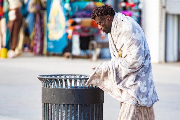 A homeless man looks in a trash can near the boardwalk at Venice Beach in Los Angeles on Jan. 27, 2021. (John Fredricks/The Epoch Times)