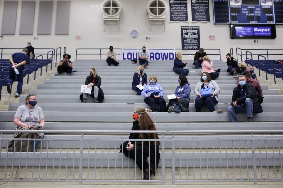 Educational staff at Kettering City Schools sit in bleachers after receiving their COVID-19 vaccine as a part of Ohio's Phase 1B vaccine distribution in Dayton, Ohio, on Feb. 10, 2021. (Megan Jelinger/AFP via Getty Images)