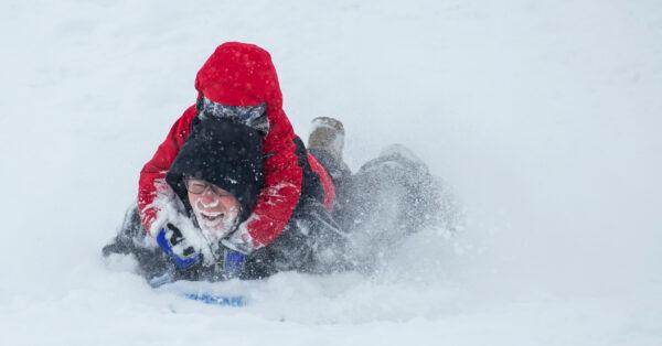 Samuel Braun, 6, let his dad, Dave, take the brunt of the frozen powder while sledding in the snowfall in Walla Walla, Wash. on Feb. 12, 2021. (Greg Lehman/Walla Walla Union-Bulletin via AP)