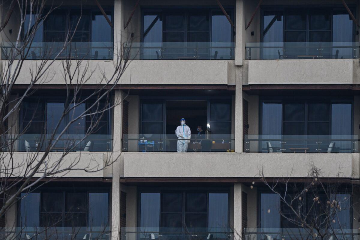 A health worker waits for members of the World Health Organization (WHO) team investigating the origins of the COVID-19 on a balcony at Wuhan Hilton Optics Valley hotel in Wuhan, China's central Hubei Province on Feb. 6, 2021. (Hector Retamal/AFP via Getty Images)