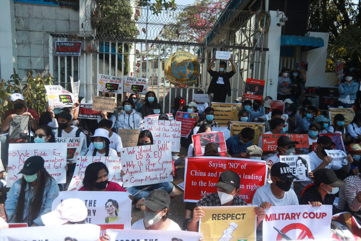 Anti-coup protesters hold posters as they gather outside the U.N. Information Office in Yangon, Burma, on Feb. 14, 2021. (AP Photo)