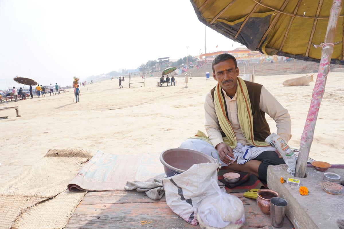 Rakesh Tiwari, a priest sits at the Assi Ghat bank of the Ganges waiting for pilgrims at the ancient city of Kashi on Feb. 12, 2021. (Venus Upadhayaya/Epoch Times)