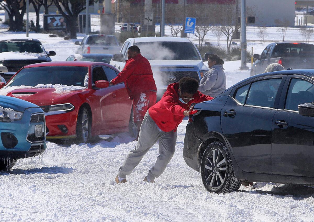 People push a car free after spinning out in the snow in Waco, Texas, on Feb. 15, 2021. (Jerry Larson/Waco Tribune-Herald via AP)