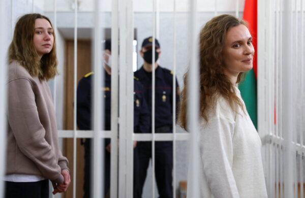 Katsiaryna Andreyeva and Darya Chultsova, Belarusian journalists working for the Polish television channel Belsat accused of coordinating mass protests in 2020 by broadcasting live reports, stand inside a defendants' cage during a court hearing in Minsk, Belarus, on Feb. 18, 2021. (Stringer/Reuters)