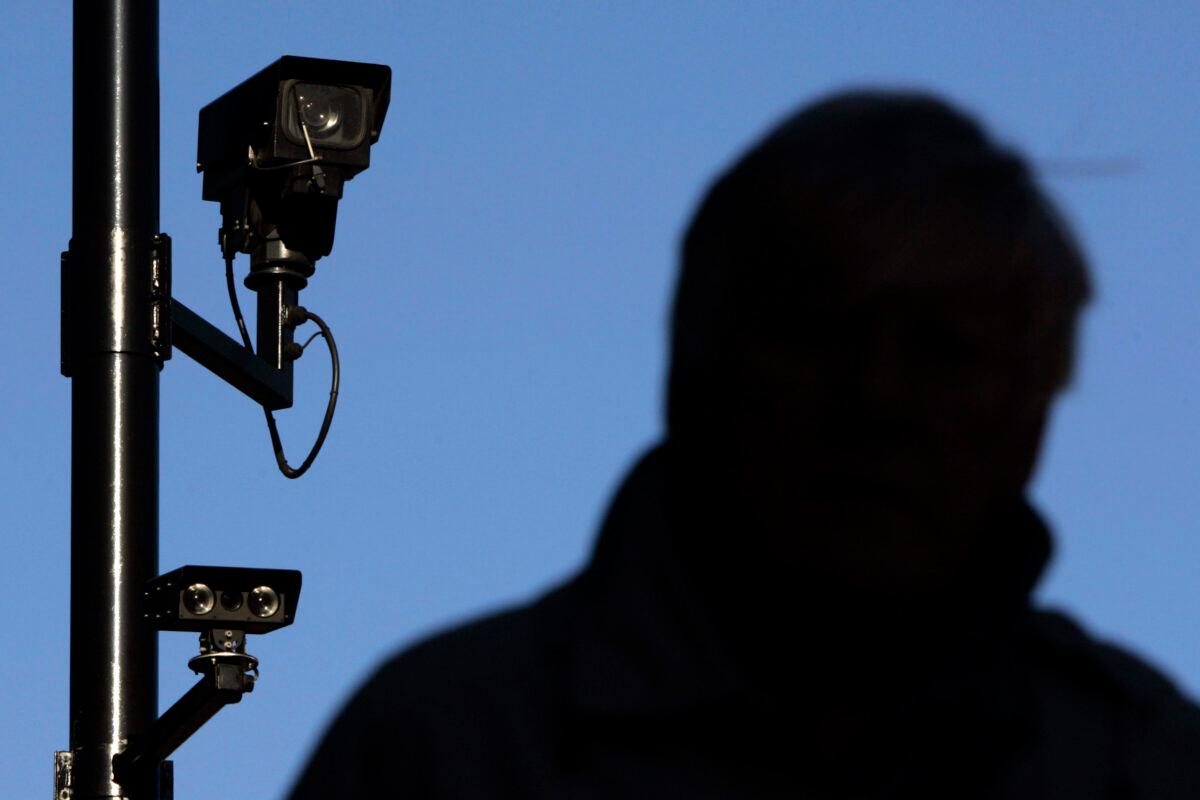 A security camera overlooks a man as he walks down a street in London, on Nov. 2, 2006. (Luke MacGregor/Reuters)