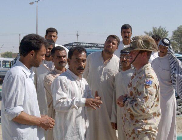 Rober Noble, then a Lieutenant Colonel, talks to Musarb, a local taxi driver, and members of the Ar Rumaythah community about the bus depot refurbished with Australian funds on Oct. 8, 2005. (SGT Craig Sharp/ADF)