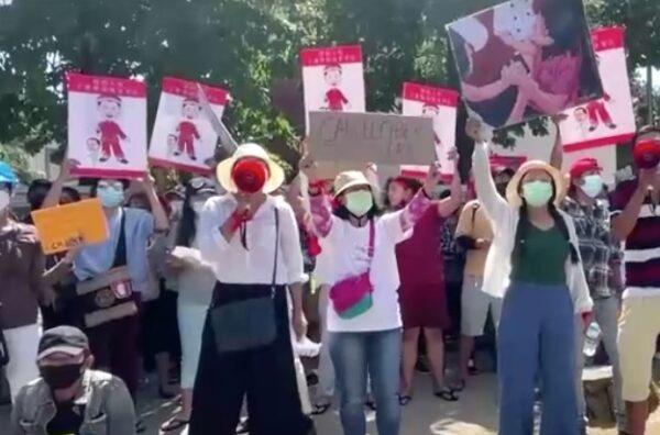 Protesters outside Chinese Embassy in Burma hold up posters of Xi Jinping and Min Aung Hlaing. (Screenshot of Reuters video)