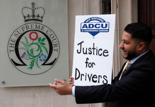 Yaseen Islam, Uber driver and president of the App Drivers & Couriers Union (ADCU), poses with a poster outside the Supreme Court in London, on Feb. 19, 2021. The UK Supreme Court ruled Friday that Uber drivers should be classed as “workers” and not self-employed. (Frank Augstein /AP Photo)