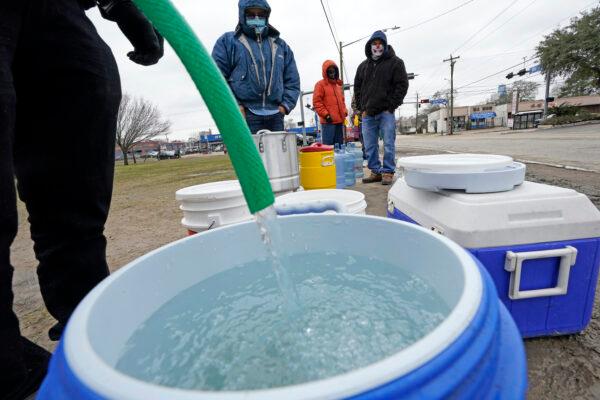 A water bucket is filled as others wait in near-freezing temperatures to use a hose from a public park spigot in Houston, Texas, on Feb. 18, 2021. (David J. Phillip/AP Photo)