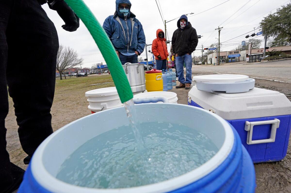A water bucket is filled as others wait in near freezing temperatures to use a hose from public park spigot in Houston, Texas on Feb. 18, 2021. (David J. Phillip/AP Photo)