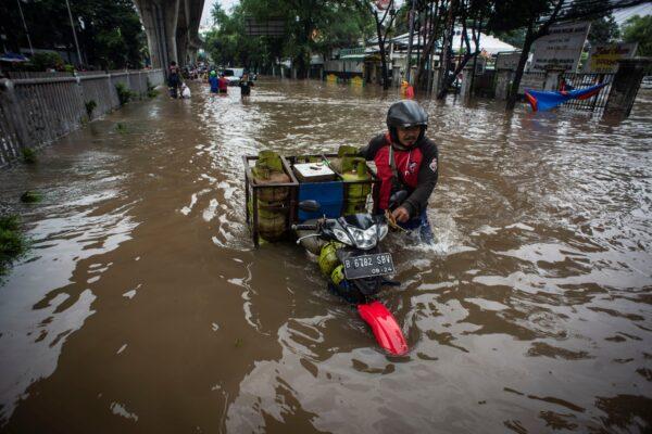 Man pushes his motorbike through water in an area affected by floods following heavy rains in Jakarta, Indonesia, on Feb. 20, 2021. (Aprillio Akbar/Antara Foto via Reuters)