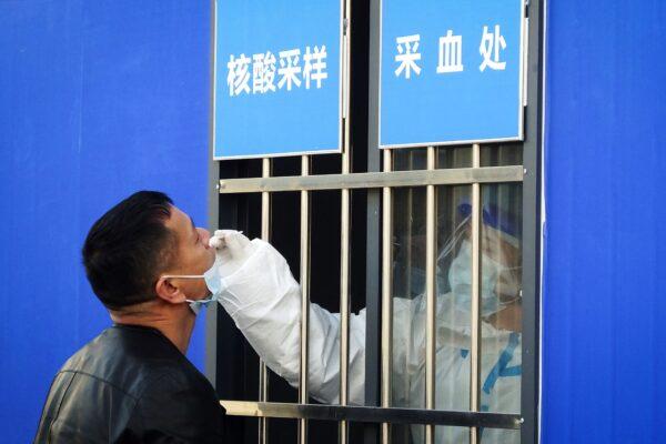 A health worker collects a nasal swab sample from a man to test for COVID-19 at a testing site outside Yichangdong Railway Station in Yichang, in Hubei Province, China, on Jan. 28, 2021. (STR/AFP via Getty Images)