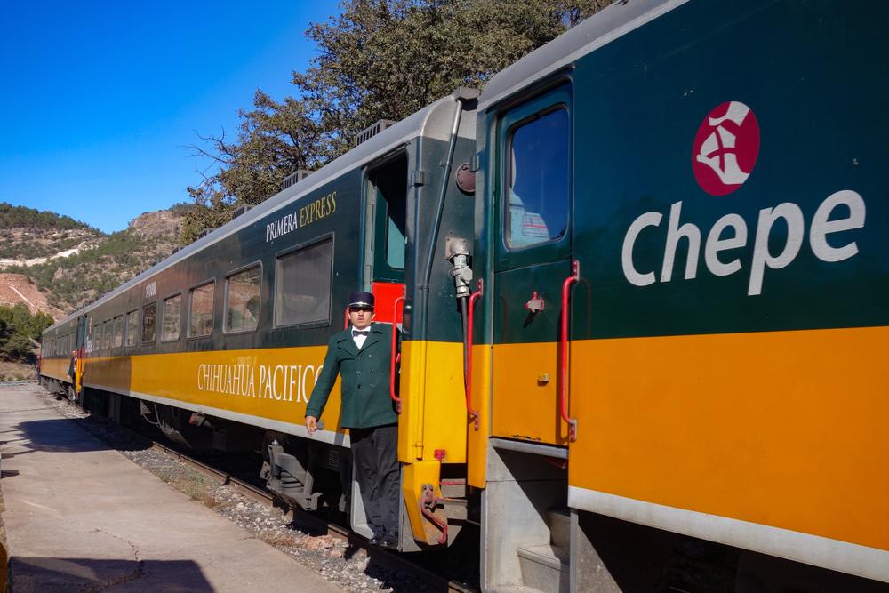 A conductor leans out of the Chihuahua-Pacifico (El Chepe) train at the Bahuichivo railway station. (Kylie Nicholson/Shutterstock)
