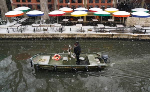 A Park Policeman patrols along the River Walk as snow falls, Thursday, Feb. 18, 2021, in San Antonio. Snow, ice and sub-freezing weather continue to wreak havoc on the state's power grid and utilities. (AP Photo/Eric Gay)