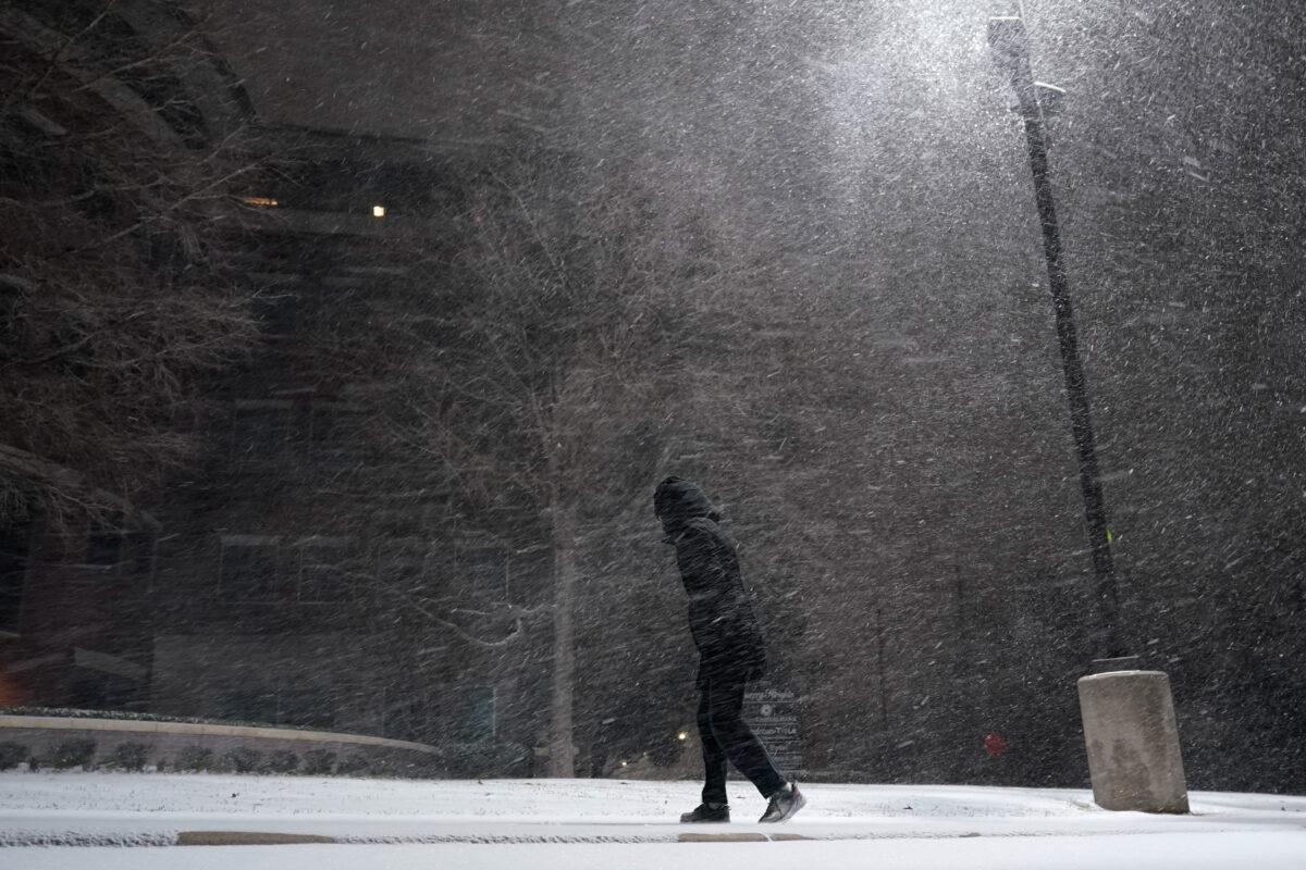 A woman walks through falling snow in San Antonio on Feb. 14, 2021, during a winter storm that caused much of Texas' power grid to collapse. (Eric Gay/AP Photo)