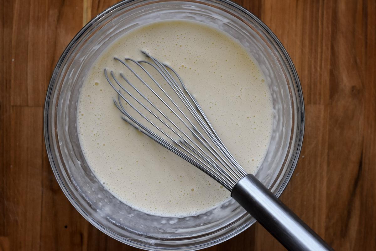 Continue adding the milk, switching to a whisk, until the batter has the consistency of heavy cream. (Audrey Le Goff)