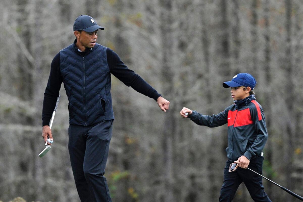 Tiger Woods (L) gives his son Charlie (C) a fist bump after Charlie made a putt on the 12th green during a practice round of the Father Son Challenge golf tournament, in Orlando, Fla., on Dec. 17, 2020. (Phelan M. Ebenhack/AP Photo)