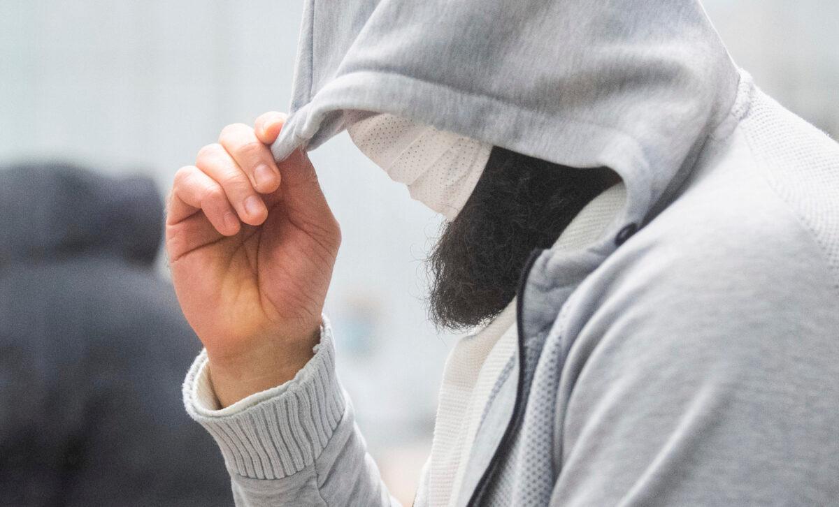 A man who calls himself Abu Walaa, alleged leader of the ISIS terrorist group in Germany, hides his face at the Higher Regional Court in Celle, Germany, on Feb. 24, 2021. The state court in Celle in northern Germany convicted the 37-year-old Iraqi citizen who goes by the alias Abu Walaa of membership in and support for a terrorist organization. (Julian Stratenschulte/DPA via AP, Pool)