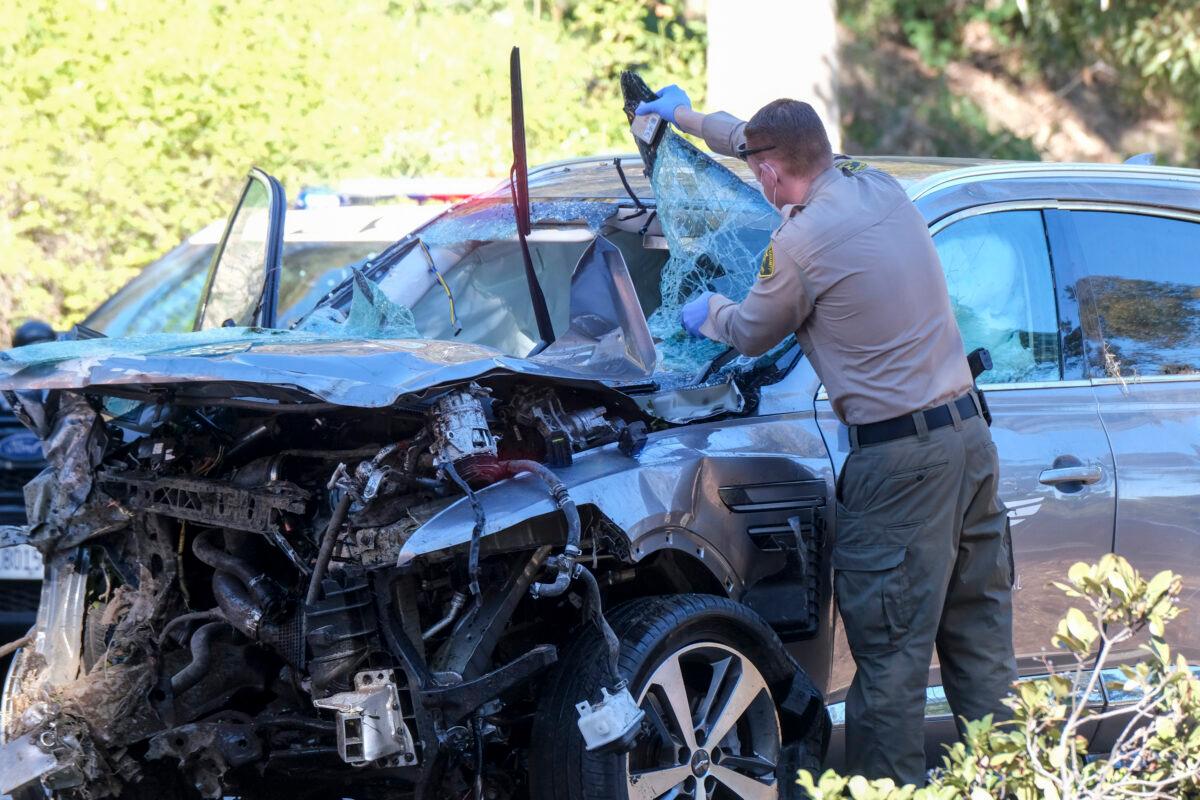 A law enforcement officer looks over a damaged vehicle following a rollover accident involving golfer Tiger Woods, in the Rancho Palos Verdes suburb of Los Angeles, Calif., on Feb. 23, 2021. (Ringo H.W. Chiu/AP Photo)