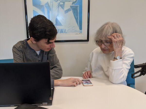 Sam Friedman assists an elderly woman with her iPhone. (Courtesy of Sam Friedman)
