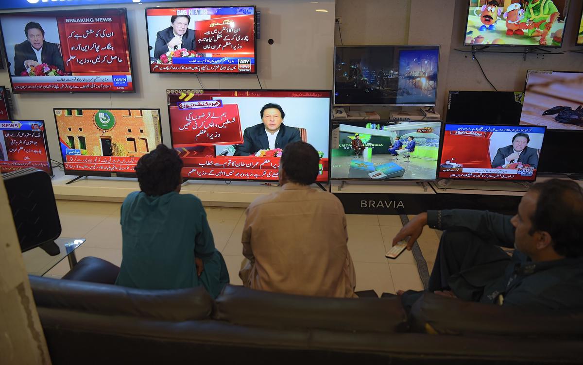Pakistani residents watch the speech of Prime Minister Imran Khan as he addresses the nation after his visit to Saudi Arabia, at an electronic shop in Islamabad on Oct. 24, 2018. (Aamir Qureshi/AFP via Getty Images)