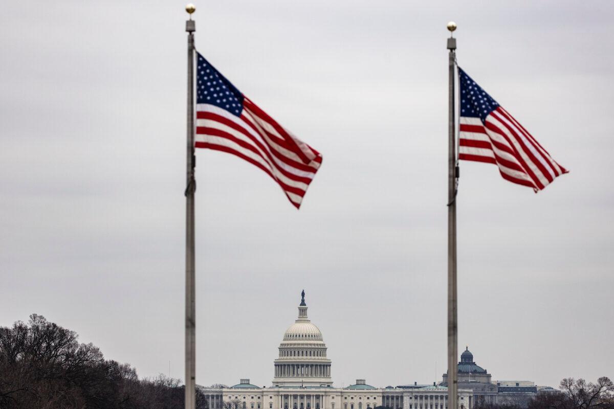 The U.S. Capitol building is seen past American flags at the base of the Washington Monument in Washington on Feb. 15, 2021. (Samuel Corum/Getty Images)