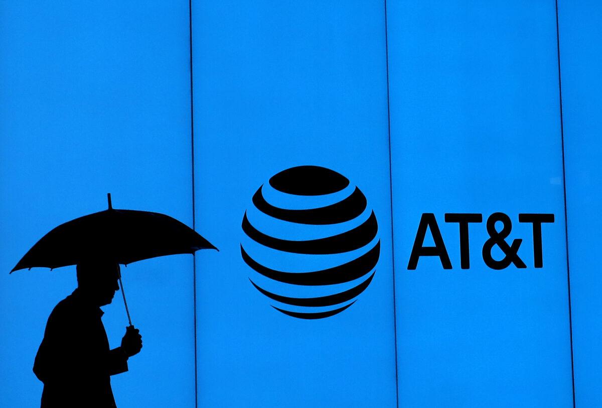 A man walks with an umbrella outside of AT&T corporate headquarters in Dallas, Texas on March 13, 2020. (Ronald Martinez/Getty Images)