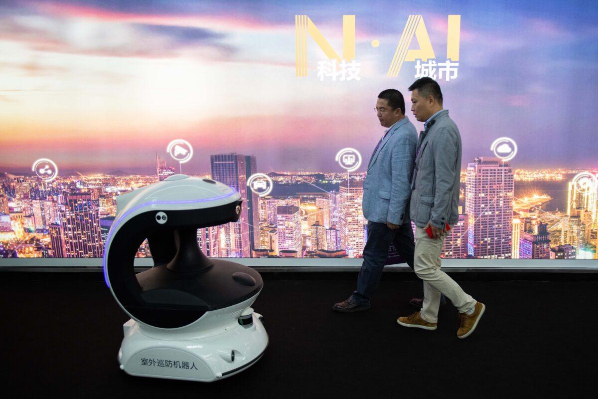 Visitors walk past an artificial intelligence security robot named APV3 with a facial recognition system at the 14th China International Exhibition on Public Safety and Security at the China International Exhibition Center in Beijing on Oct. 24, 2018. (Nicolas Asfouri/AFP via Getty Images)