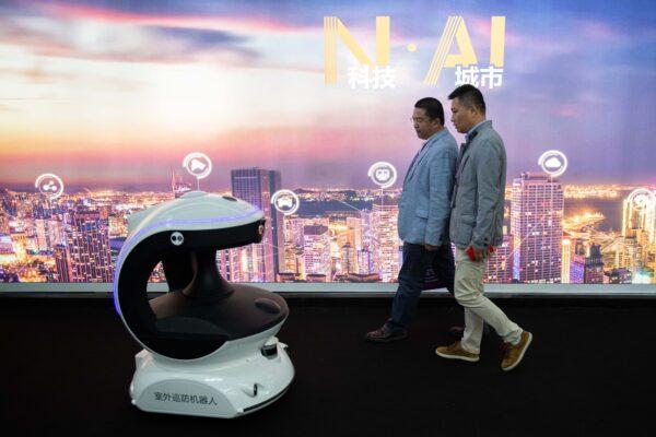 Visitors walk past an AI (artificial intelligence) security robot named APV3 with a facial recognition system at the 14th China International Exhibition on Public Safety and Security at the China International Exhibition Center in Beijing on Oct. 24, 2018. (Nicolas Asfouri/AFP via Getty Images)