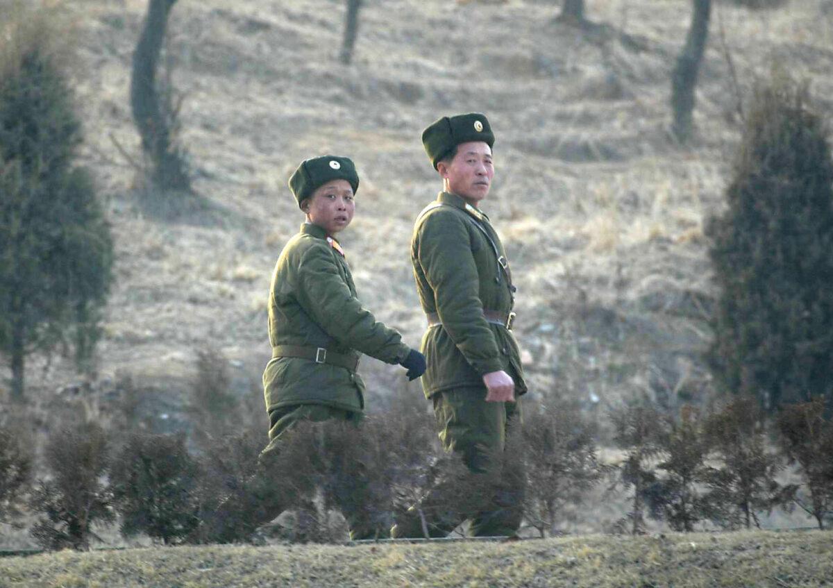 Two North Korean soldiers walk along a road leading to their camp on the outskirts of Pyongyang on Feb. 14, 2003. (Goh Chai Hin/AFP via Getty Images)