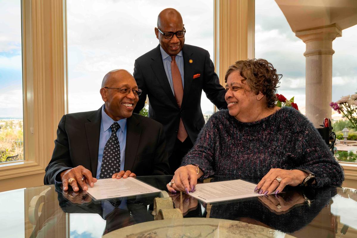 Calvin Tyler Jr. and his wife, Tina, smile at each other after signing a pledge for $20 million to his alma mater, Morgan State University, as the university's president, David K. Wilson, looks on at the Tylers' home in Las Vegas on Feb. 20, 2021. (Paul "P.A." Greene/Morgan State University via AP)