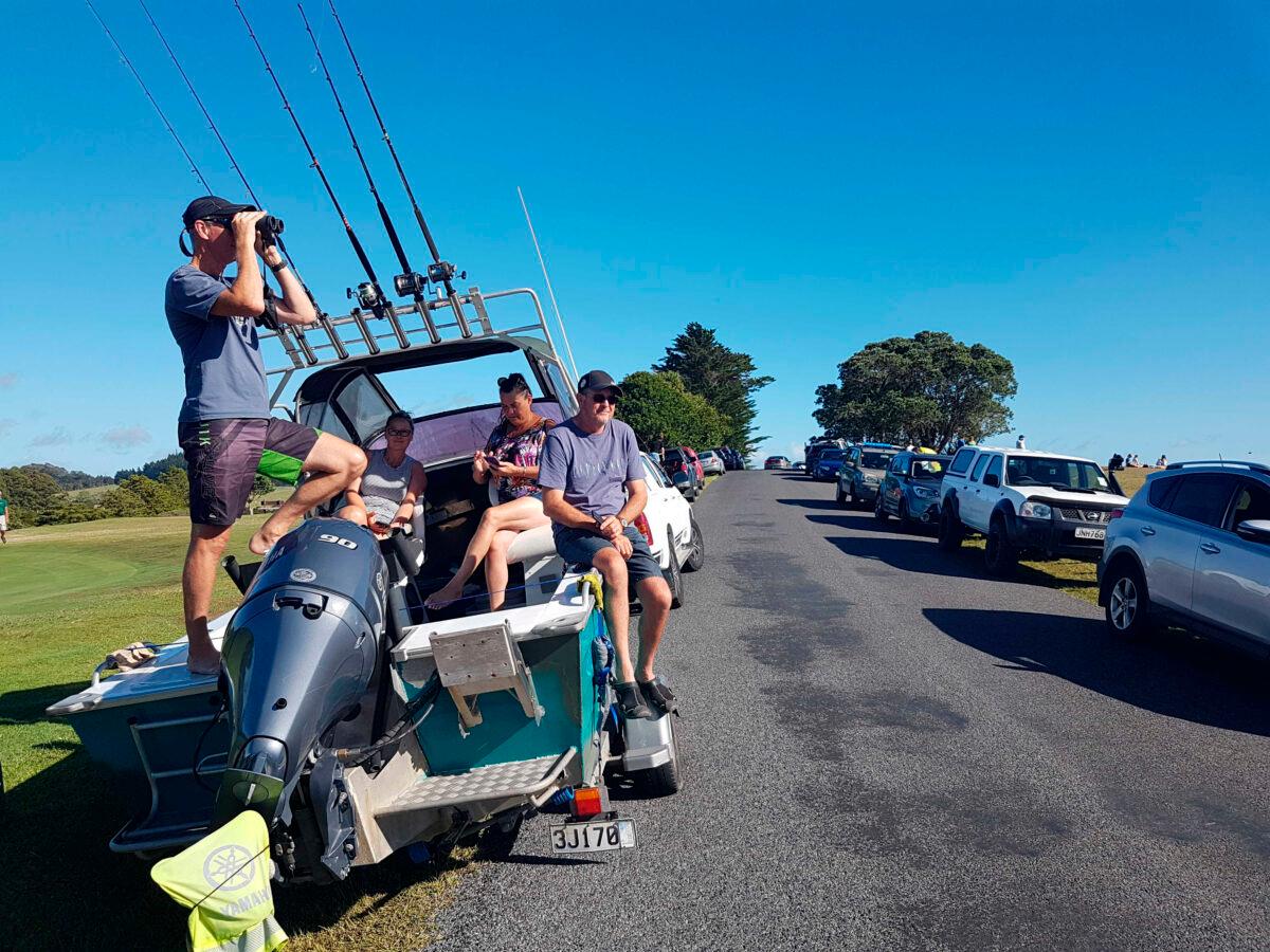 John Fitzgerald, left, on holidays with his wife Rita and friends, scans the horizon from high ground for any sign of a tsunami near Waitangi, New Zealand, Friday, March 5, 2021. (Peter De Graaf/New Zealand Herald via AP)