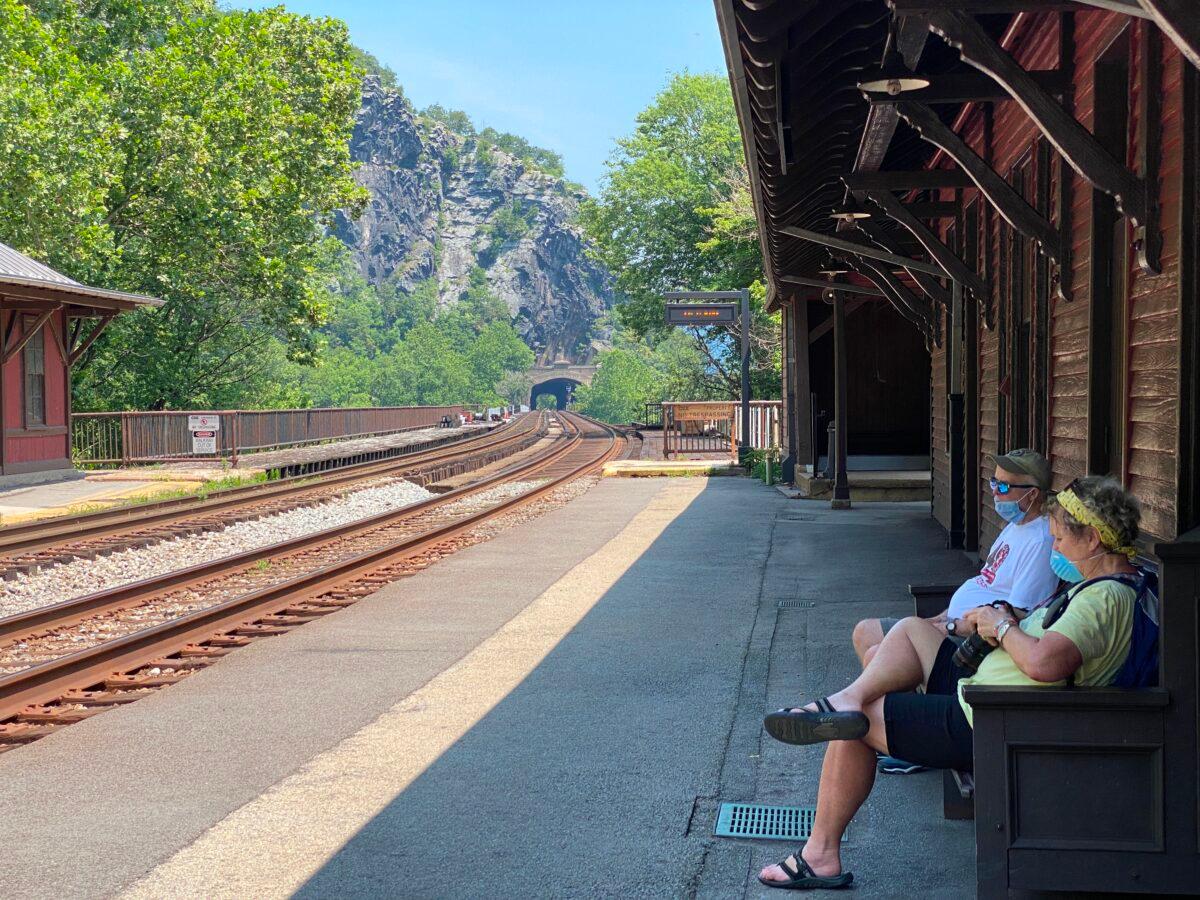A couple wearing masks wait for the train arrival at Harpers Ferry station in West Virginia, on July 3, 2020. (Daniel Slim/AFP via Getty Images)