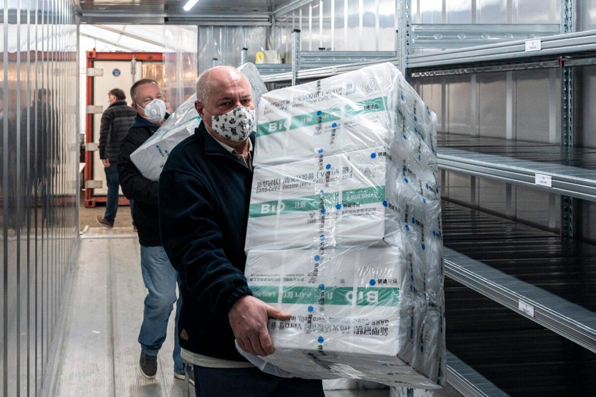 Employees unload the newly arrived coronavirus vaccines from Chinese pharmaceutical company Sinopharm at the logistics base set up to in the parking lot of the government office in the 13th district of Budapest, Hungary, on March 3, 2021. (Zsolt Szigetvary/MTI via AP)