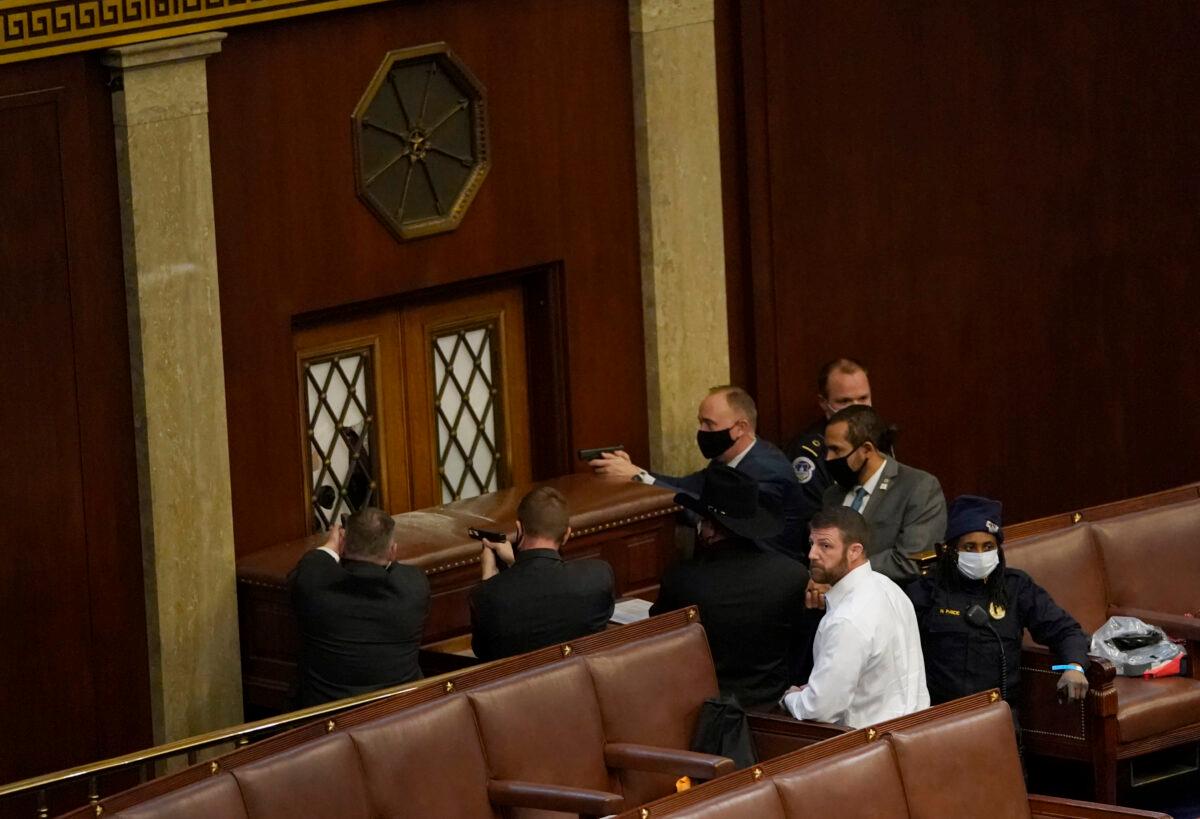 U.S. Capitol police officers point their guns at a door that was vandalized in the House Chamber during a joint session of Congress in Washington, on Jan. 6, 2021. (Drew Angerer/Getty Images)
