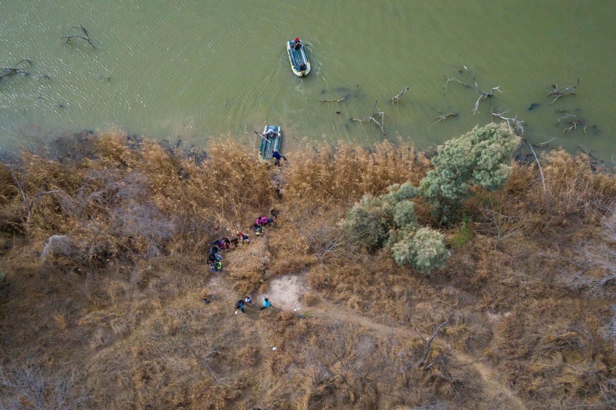 Family units and unaccompanied minors climb the banks of the Rio Grande River into the United States as smugglers on rafts prepare to return to Mexico in Penitas, Texas on March 5, 2021. (Adrees Latif/Reuters)