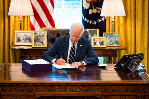 President Joe Biden signs a bill in the Oval Office of the White House in Washington on March 11, 2021. (Doug Mills/Pool/Getty Images)
