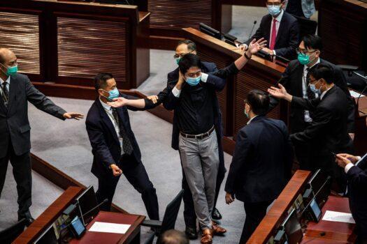 Pro-democracy legislator Ted Hui (C) is removed by security guards after throwing a jar containing a foul-smelling liquid onto the floor during a debate on a law that bans insulting China's national anthem at a session of the Legislative Council (Legco) in Hong Kong on June 4, 2020. (Isaac Lawrence/AFP via Getty Images)