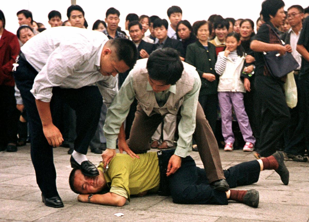 Police detain a Falun Gong protester in Tiananmen Square as a crowd watches in Beijing on Oct. 1, 2000. (Chien-min Chung/AP Photo)