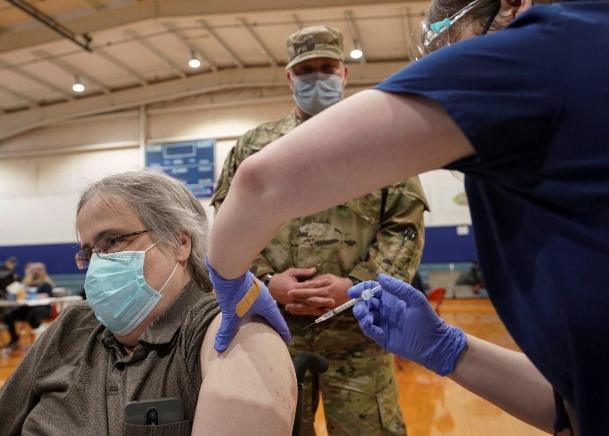 U.S. Air Force National Guard MSgt. Mathew Ramsey stands by as patient Lance Lloyd receives the COVID-19 vaccine during a community vaccination event in Martinsburg, W.Va., on March 11, 2021. (Kevin Lamarque/Reuters)