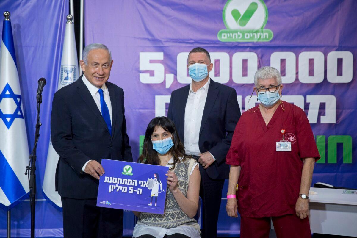 Israeli Prime Minister Benjamin Netanyahu, left, and Health Minister Yuli Edelstein, center, meet the Israeli citizen who is the 5 millionth person to be vaccinated in Israel, in Tel Aviv, Israel on March 8, 2021. (Miriam Alster/Pool via AP)
