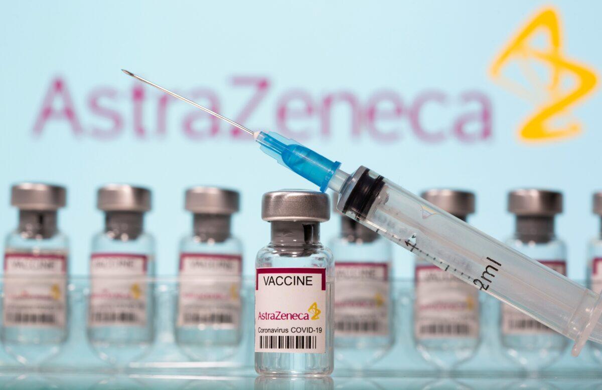 Vials labelled "AstraZeneca COVID-19 Coronavirus Vaccine" and a syringe are seen in front of a displayed AstraZeneca logo in this illustration, on March 10, 2021. (Dado Ruvic/Reuters, Illustration/File Photo)
