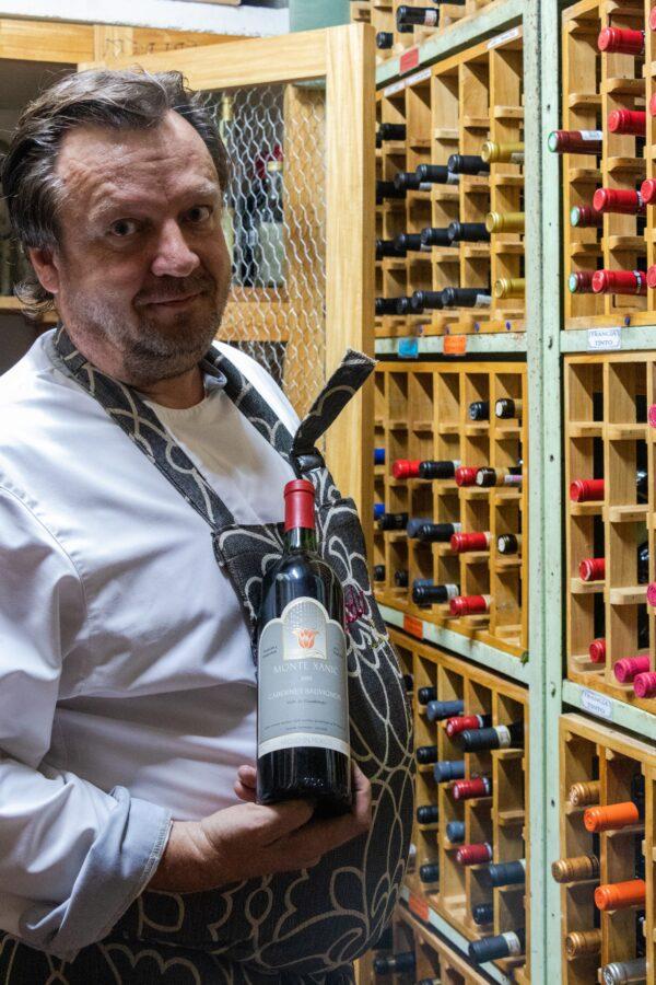 Bernhard Güt, chef and owner of Trio, opened the restaurant in 1997. Pictured in the wine cellar, he holds a bottle of Monte Xanic 1995 Cabernet Sauvignon. (Dennis Lennox)